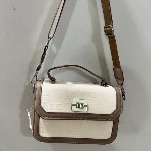 A structured handbag with a cream-colored embossed front flap and brown trim, featuring a top handle, a long brown shoulder strap, and a silver-tone turn-lock clasp, shown hanging against a plain light gray wall.